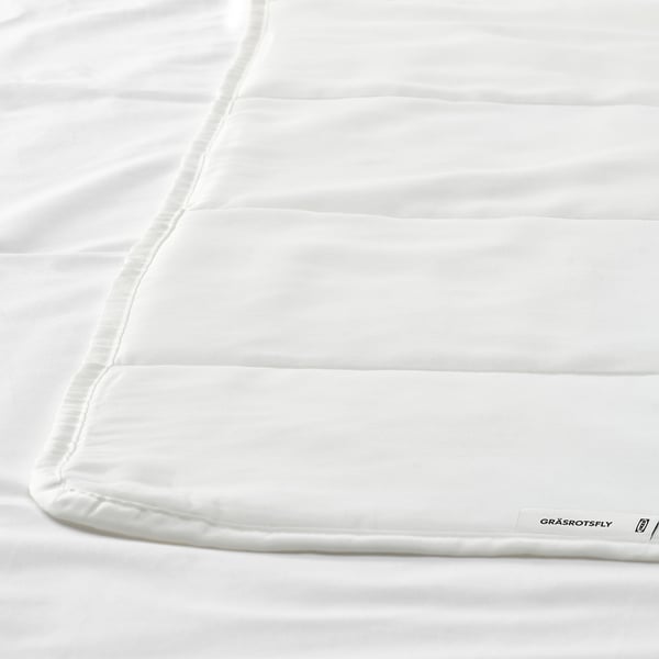 Nahaufnahme einer glatten, weißen Bettdecke mit dezenten Nähten, die hochwertigen Stoff zeigt.