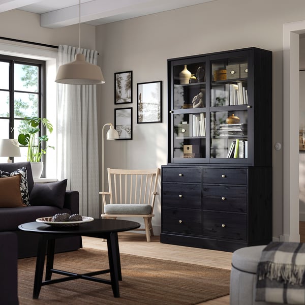 HAVSTA Display & Truhe im modernen Wohnzimmer mit Büchern, Vasen, grauer Couch, Holzstuhl und großem Fenster.