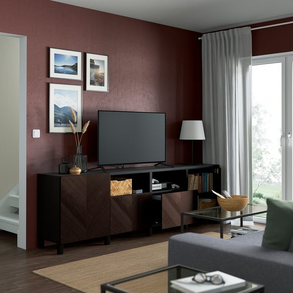 Modernes Wohnzimmer mit kastanienbraunen Wänden, Flachbildfernseher, Couchtisch aus Glas und grauem Sofa.