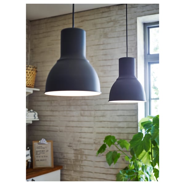Zwei schwarze Pendelleuchten begrünen den Holztisch vor der Backsteinwand.