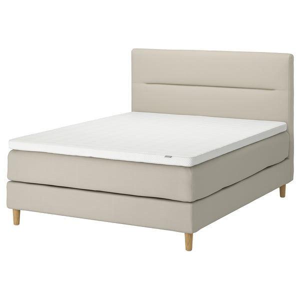 Modernes, beiges Divan-Bett mit weichem Kopfteil, leichten Holzbeinen und weißer Matratze.