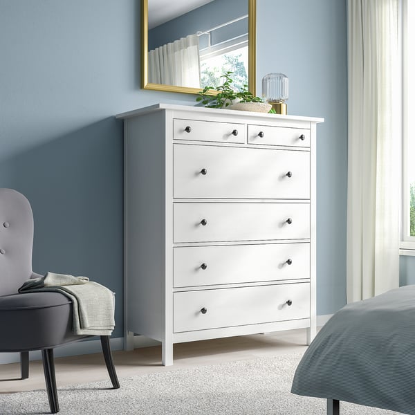 Weiße HEMNES Kommode mit 6 Schubladen aus massiver Kiefer, traditioneller Stil, hoch und schlank, passt gut neben Bett und Spiegel, mit goldenen und grünen Akzenten.