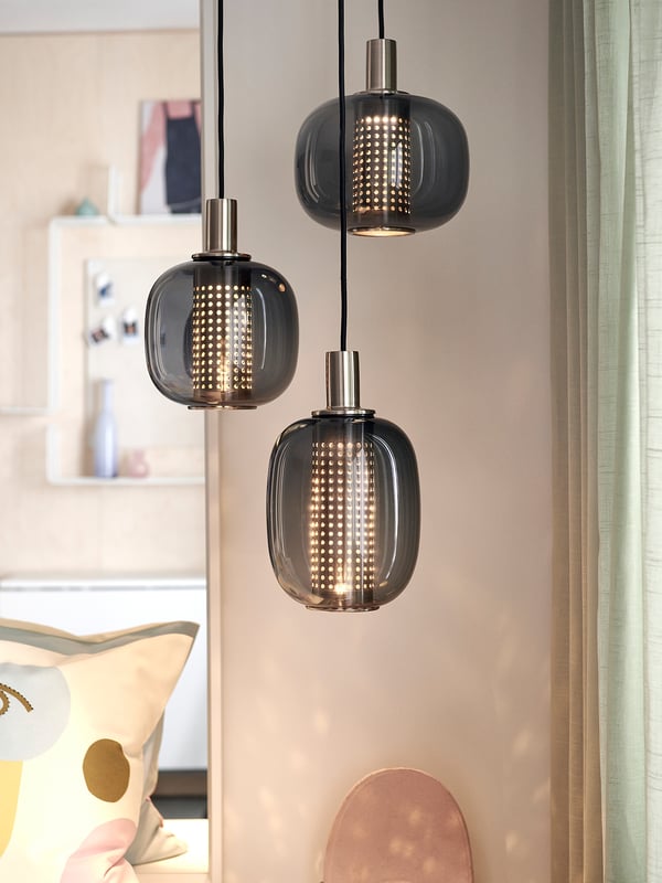 Drei Pendelleuchten aus Rauchglas mit perforierten Schirmen, Messing-Finish.