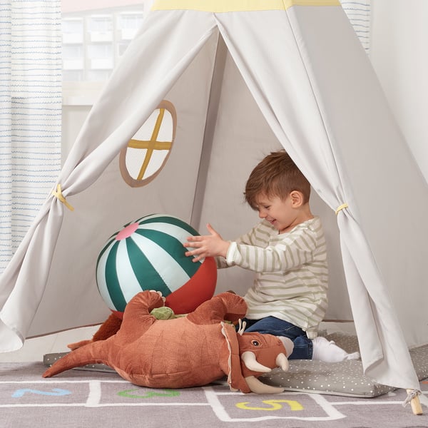 Junge im Zelt mit Ball und Spielzeugmammut.