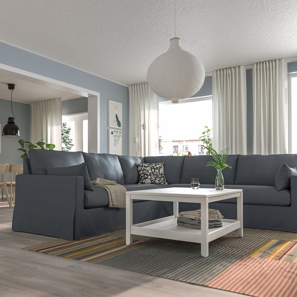 Modernes Wohnzimmer mit großem grauem Sofa, weißem Couchtisch und Hängeleuchte.