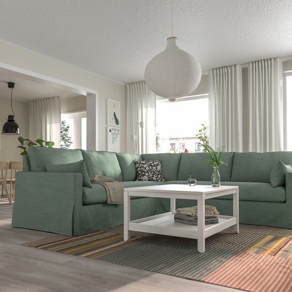 Wohnzimmer mit HYLTARP-Sofa, Teppich, Couchtisch und Vorhängen.