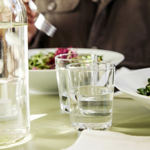 Tisch gedeckt mit klaren Gläsern und Wasserkrug, bereit zum Essen.