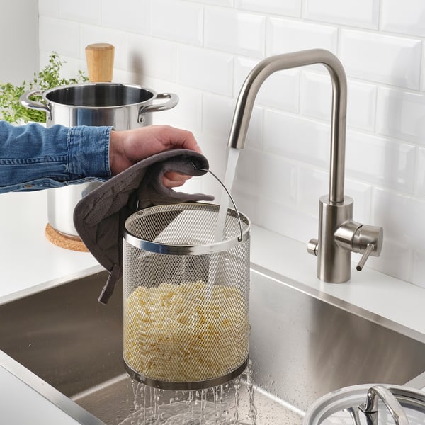 Spülen von Lebensmitteln im Sieb unter dem Wasserhahn.