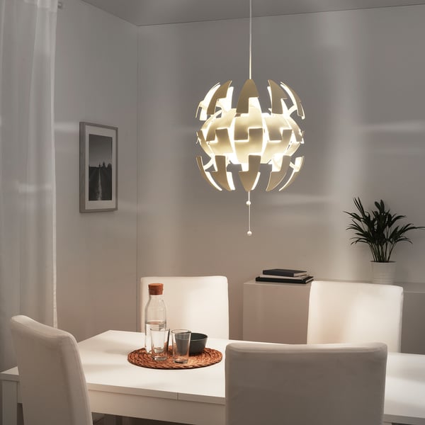 Weiße IKEA PS 2014 Pendelleuchte über dem Esstisch, die ein sanftes Licht wirft.