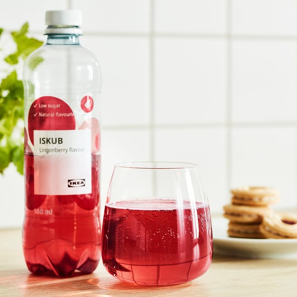 Preiselbeer-Trinkflasche mit wenig Zucker neben einem Glas und Keksen.