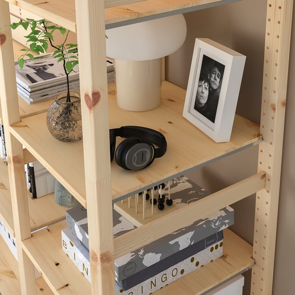 Holzregal mit Gegenständen: Pflanze, Lampe, Foto, Kopfhörer und Boxen.