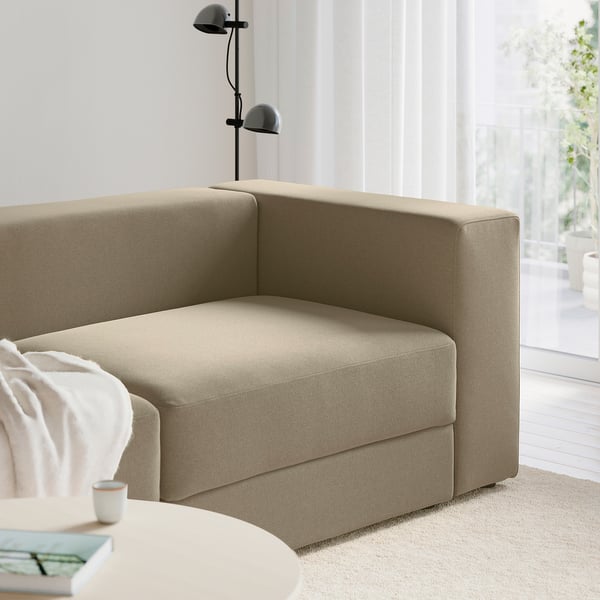 Ein modernes, beiges moduläres Sofa, Teil der JÄTTEBO-Serie , mit eingebautem Stausitz, in der Nähe eines Fensters.