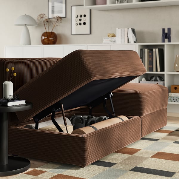 Braunes JÄTTEBO-Sofa mit offenem Stauraum, freizügige Decke und Kissen.