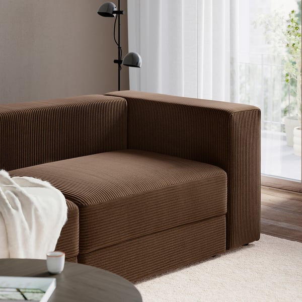 Braunes JÄTTEBO modulares Sofa mit bequemen Polstern und Stauraum unter den Sitzen, in der Nähe eines Fensters positioniert.