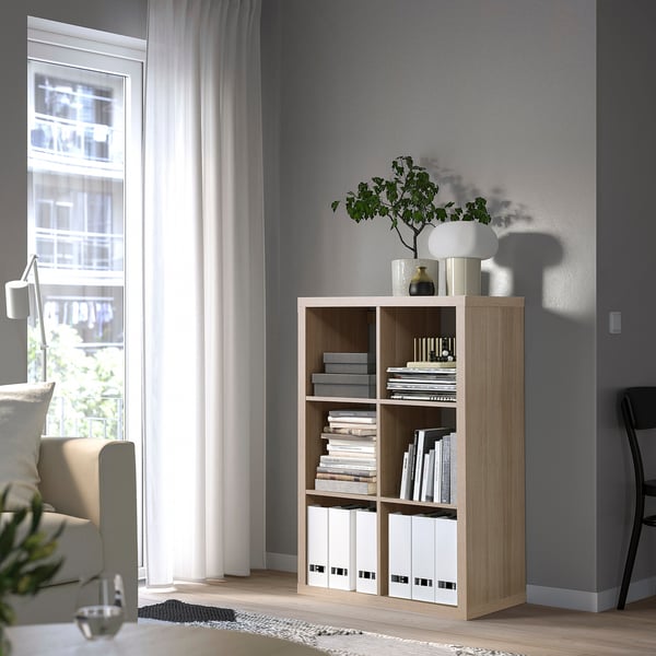 KALLAX Regale, helles Holz, in der Nähe des Fensters, für Bücher und Dekoration. Hohe, einfache, klare Linien.
