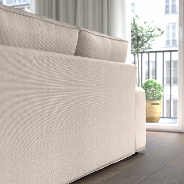 Ein gemütliches, helles Sofa mit Kissen, ideal zum Entspannen, in der Nähe eines großen Fensters mit Blick auf die Stadt.