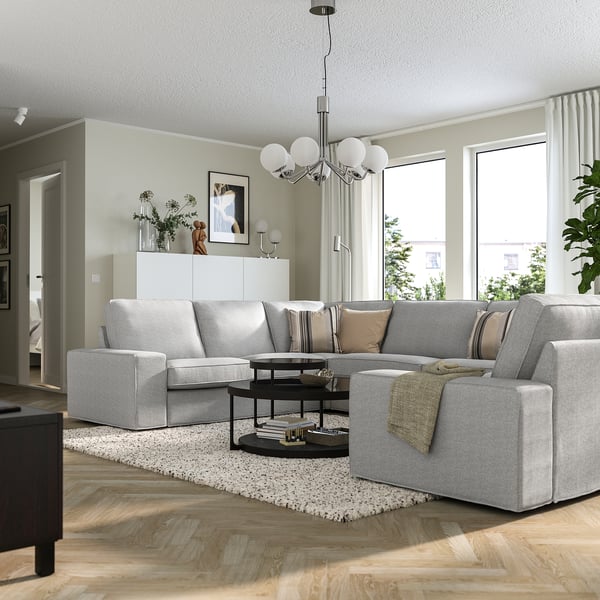 KIVIK graues Sofa mit 3-Sitzer und Chaiselongue, Holzböden, große Fenster, schwarzer Couchtisch.
