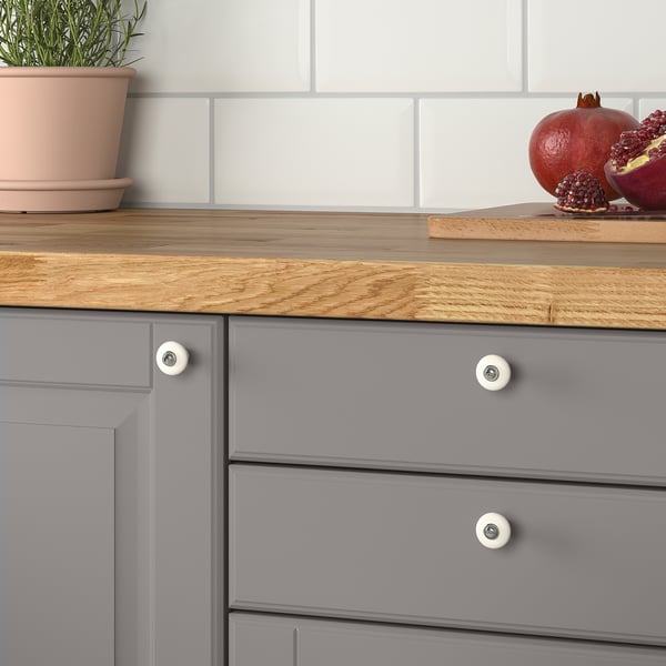 Graue Küchenschublade mit Holzplatte, KLINGSTORP-Knöpfen, Topfpflanze und Granatäpfeln.