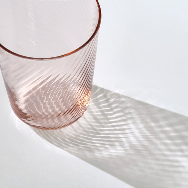 Elegantes, dünnes Glas mit glatter Außenseite und strukturiertem Inneren, das zarte Schatten wirft.