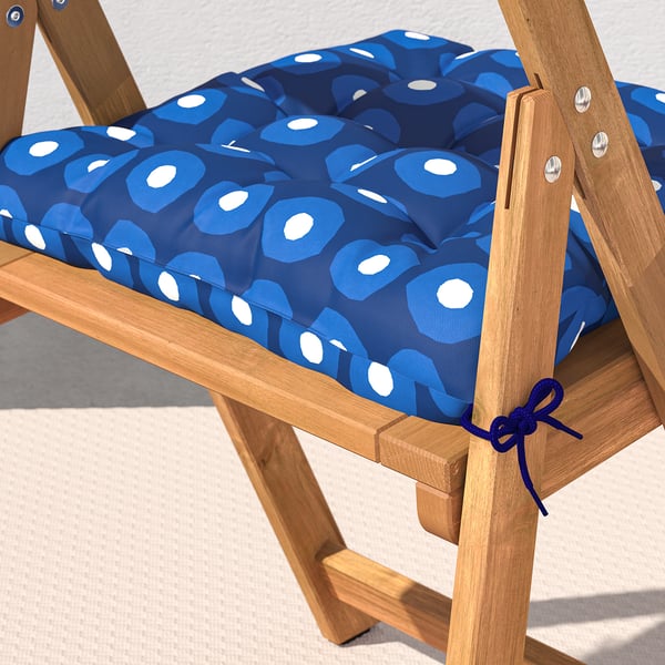 Ein Klappstuhl aus Holz mit einem blau gemusterten Kissen, das mit Krawatten befestigt ist.