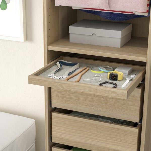 Kommode aus Holz mit offener Schublade mit Schmuckorganizer. In der Schublade befinden sich Tabletts mit Uhren, Armbändern und Halsketten.