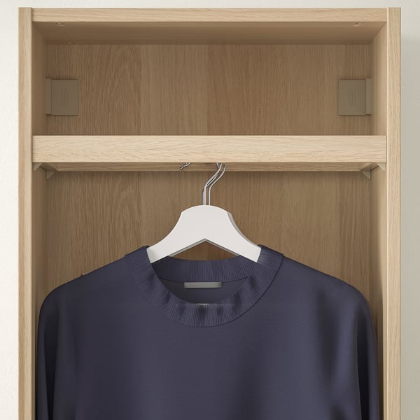 Ein hölzerner Schrankschrank mit einer Kleiderstange, die ein marineblaues Kleidungsstück auf einem weißen Kleiderbügel zeigt.