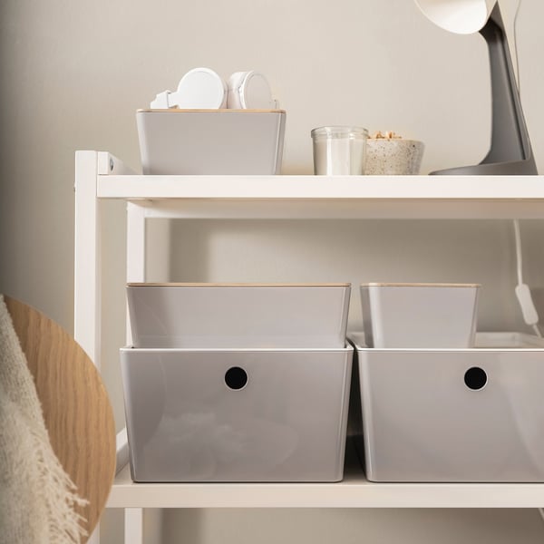 Drei KUGGIS Aufbewahrungsboxen aus grauem Kunststoff auf einem Regal; zwei größere und eine kleinere mit verschiedenen Gegenständen; Hergestellt aus teilweise recyceltem PET-Kunststoff.
