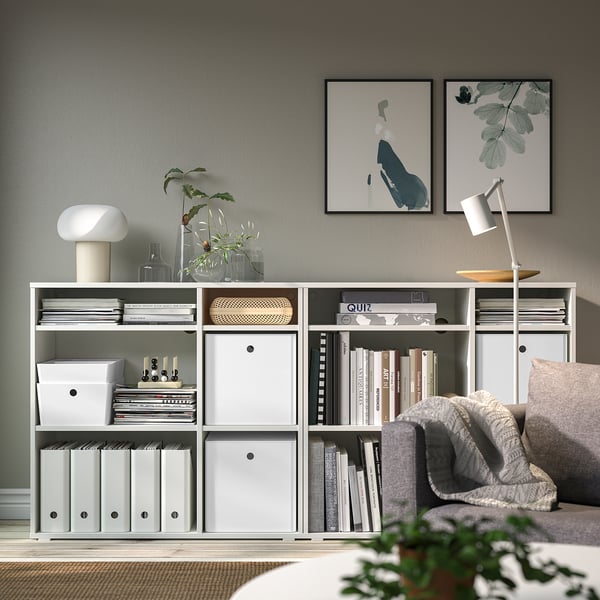 Minimalistischer Wohnraum mit KUGGIS Aufbewahrungsbox, Büchern, Dekoration und Kunstwerken.