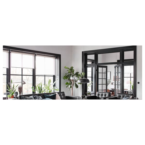 Modernes Wohnzimmer mit schwarzen Fenstern, Sofa, Pflanzen - gemütlich & stilvoll.