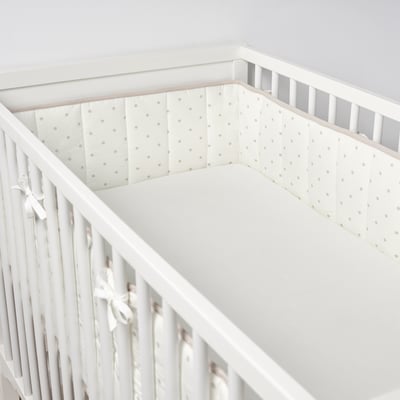 Beigefarbene Tupfen-Nestchen schützen das Baby, sicher mit Bändern befestigt.