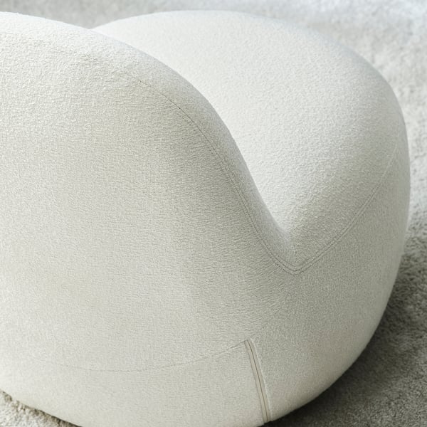 Bequemer Stuhl mit glatten, einladenden Kurven; heller Stoff, hochwertige Polsterung.