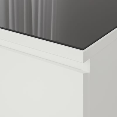 Nahaufnahme einer modernen, schlanken Glastischplatte mit klaren Linien und reflektierender Oberfläche.