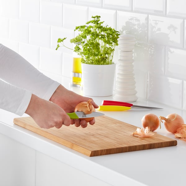 Person hackt Zwiebel auf hölzernem Schneidebrett in der Küche.