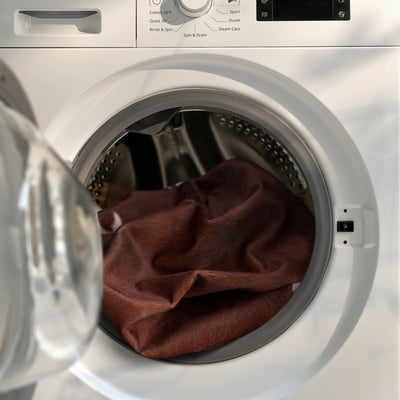 Waschmaschine mit einem Kuhleder-Teppich darin, bereit zur Reinigung.