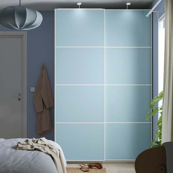 Minimalistisches Schlafzimmer mit großen blauen Schiebeschranktüren, Hängejacke und Bett mit weißer Decke.