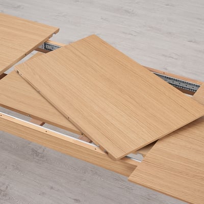 Tischplatten aus Holz mit Metallschienen, die einen Ausziehmechanismus für die Tischerweiterung zeigen.