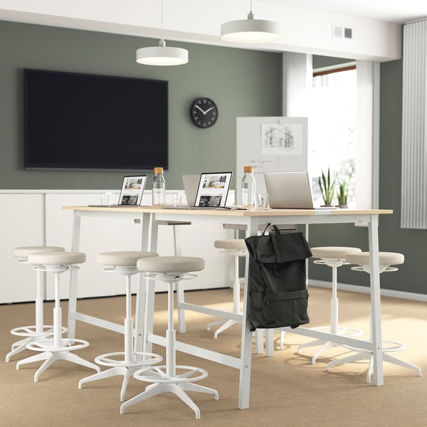 Modernes Büro mit Stehtischen, Laptops, TV, gut beleuchtet.