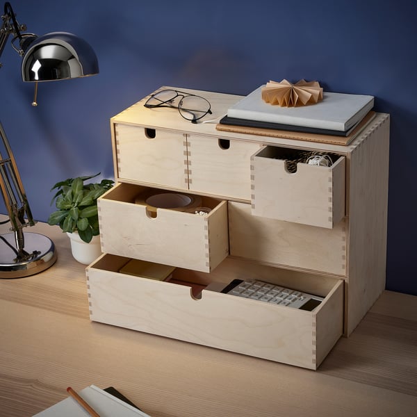 Ein Aufbewahrungsschrank aus Holz mit mehreren Schubladen, in dem verschiedene Gegenstände wie Taschenrechner, Schreibwaren und Zubehör aufbewahrt werden können.