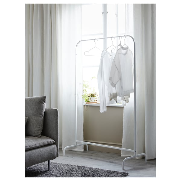 Ein minimalistischer weißer Kleiderständer von MULIG mit Kleiderbügeln steht neben einem Fenster und zeigt weiße Kleidung.