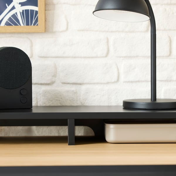 Minimalistischer Schreibtisch mit integriertem Kabelmanagement und intelligentem Stauraum, perfekt für einen aufgeräumten Arbeitsplatz. Eine moderne Lampe, ein Lautsprecher und organisierte Fächer.