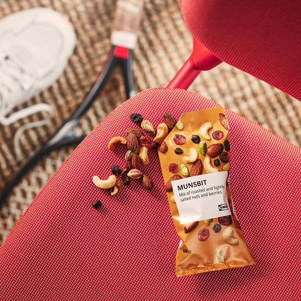 Snacktüte mit der Aufschrift MUNSBIT, mit einer Mischung aus Nüssen und Beeren, teilweise geöffnet und mit verschüttetem Inhalt.