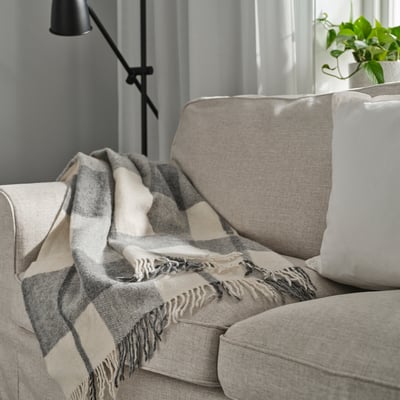 MYRULL Decke in hellgrau auf der Couch, bezüge Kissen, fransige Enden.