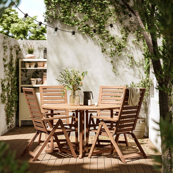 Außenterrasse mit rundem Tisch und vier Holzstühlen, braune Farbe.