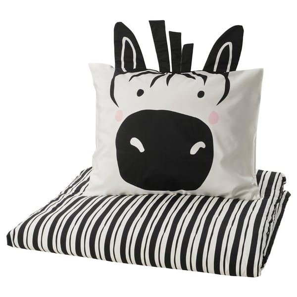 Schwarz-weißes Kissen mit Zebra-Motiv auf gestreifter Decke.
