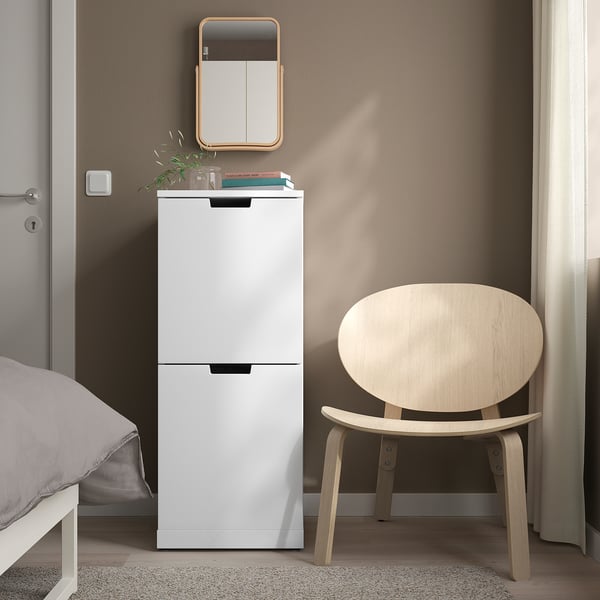 Weiße IKEA NORDLI Kommode mit 2 Schubladen zwischen Bett und Stuhl, minimalistische Ecke.