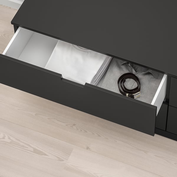 Schwarze NORDLI-Schublade offen, mit Gurt, Soft-Close-Mechanismus sichtbar, auf hellem Holzboden.