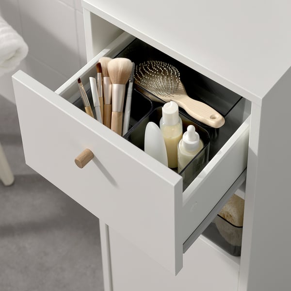 Offener Badezimmerschrank mit Make-up-Pinseln, Haarwerkzeugen und Flaschen. Das schlanke Design bietet organisierten Stauraum mit einer Schublade und Regalen.