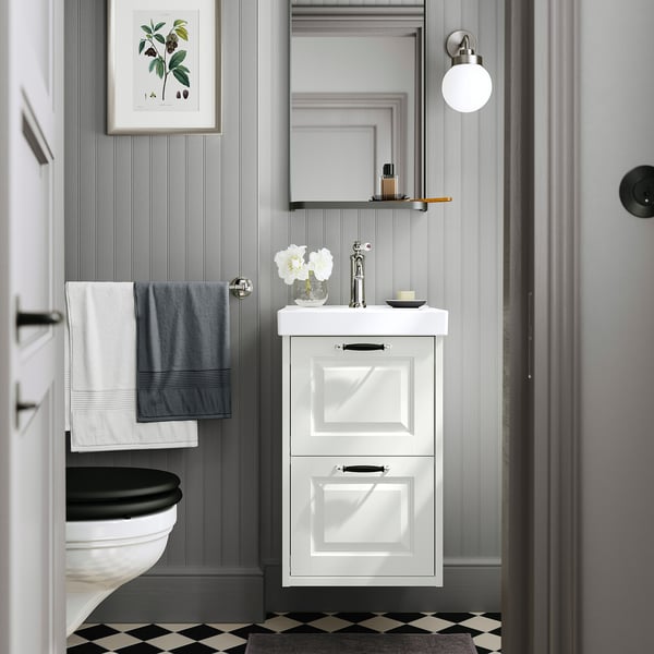 Modernes Badezimmer mit ORRSJÖN-Waschbecken, grauen Wänden, kariertem Boden, kleinem Spiegel, dunklen Beschlägen und hängenden Handtüchern.
