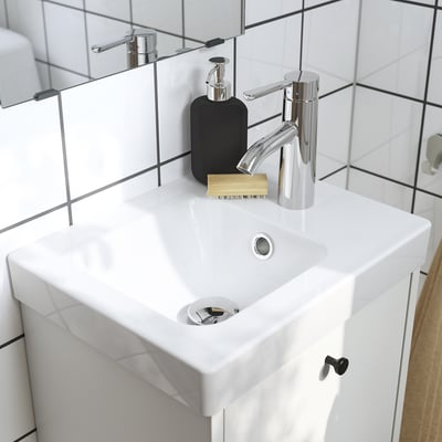 Modernes Waschbecken mit verchromtem Wasserhahn und Zubehör auf der Theke.