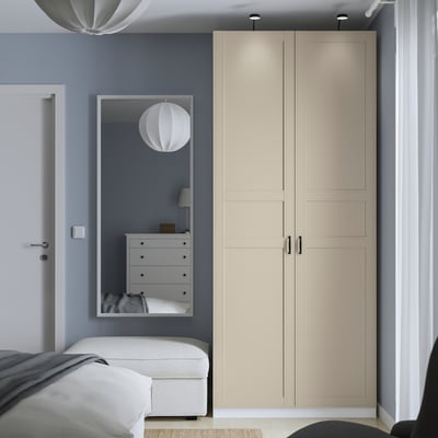 Modernes Schlafzimmer mit hohem beigem PAX-Kleiderschrank, schlankem Design, großem Spiegel, mehr Stauraum als Kommode und Bett.